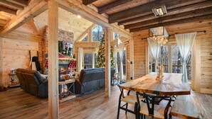Ein gemütliches Blockhaus-Interieur mit einem Holzesstisch, Stühlen, einer Couch und einem Weihnachtsbaum.