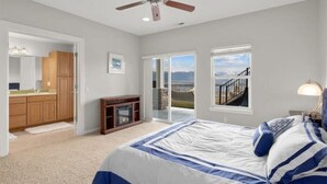 Ein Schlafzimmer mit einem großen Bett, einem Deckenventilator und Blick auf einen Balkon.