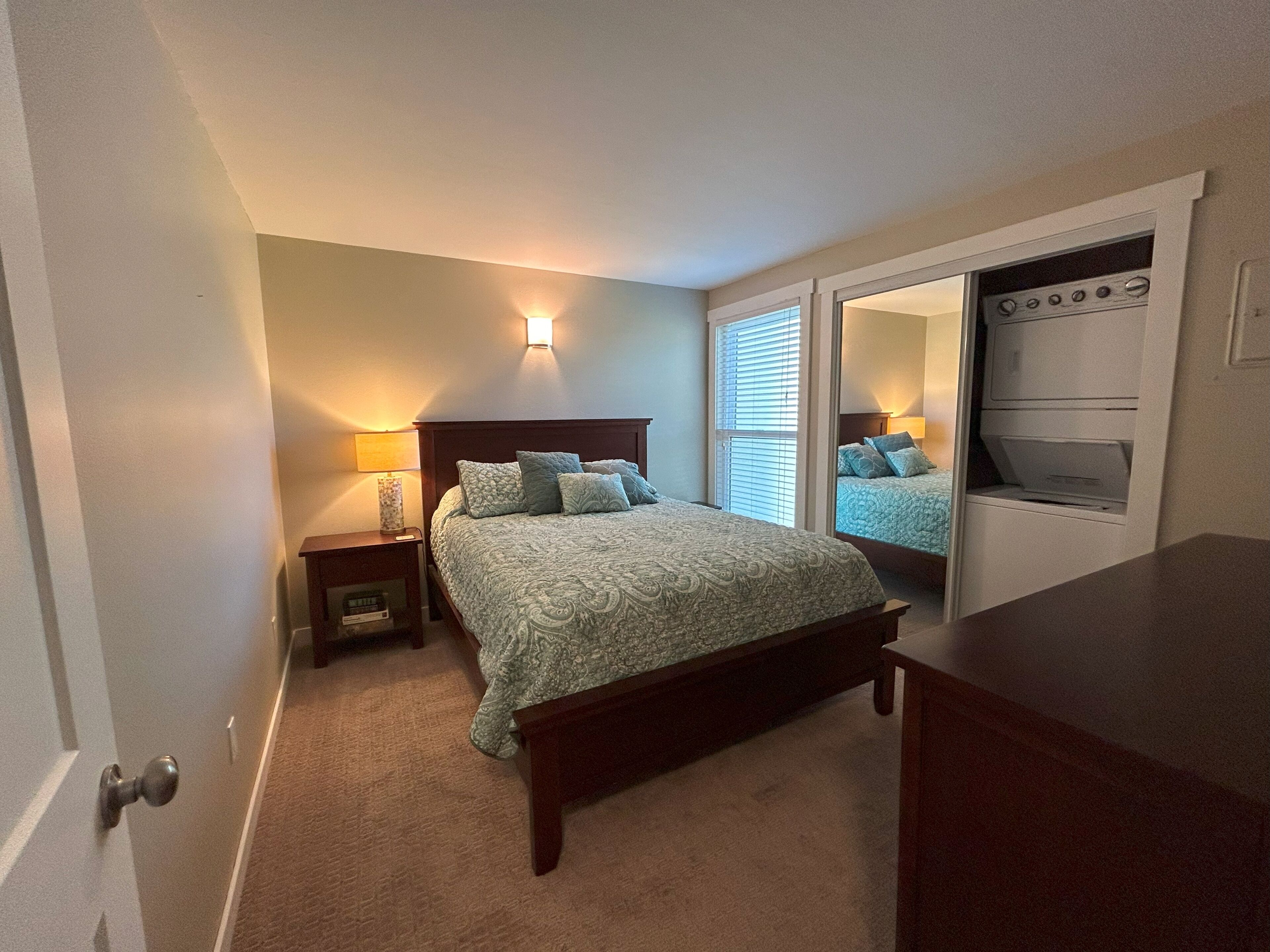 A bedroom with a bed, bedside tables, a mirror, and a built-in wardrobe.