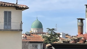 A view of a cityscape with a prominent green dome building in the distance, surrounded by buildings with terracotta roofs and a mix of architectural styles. - Porta Alla Croce Guest House (Florence)