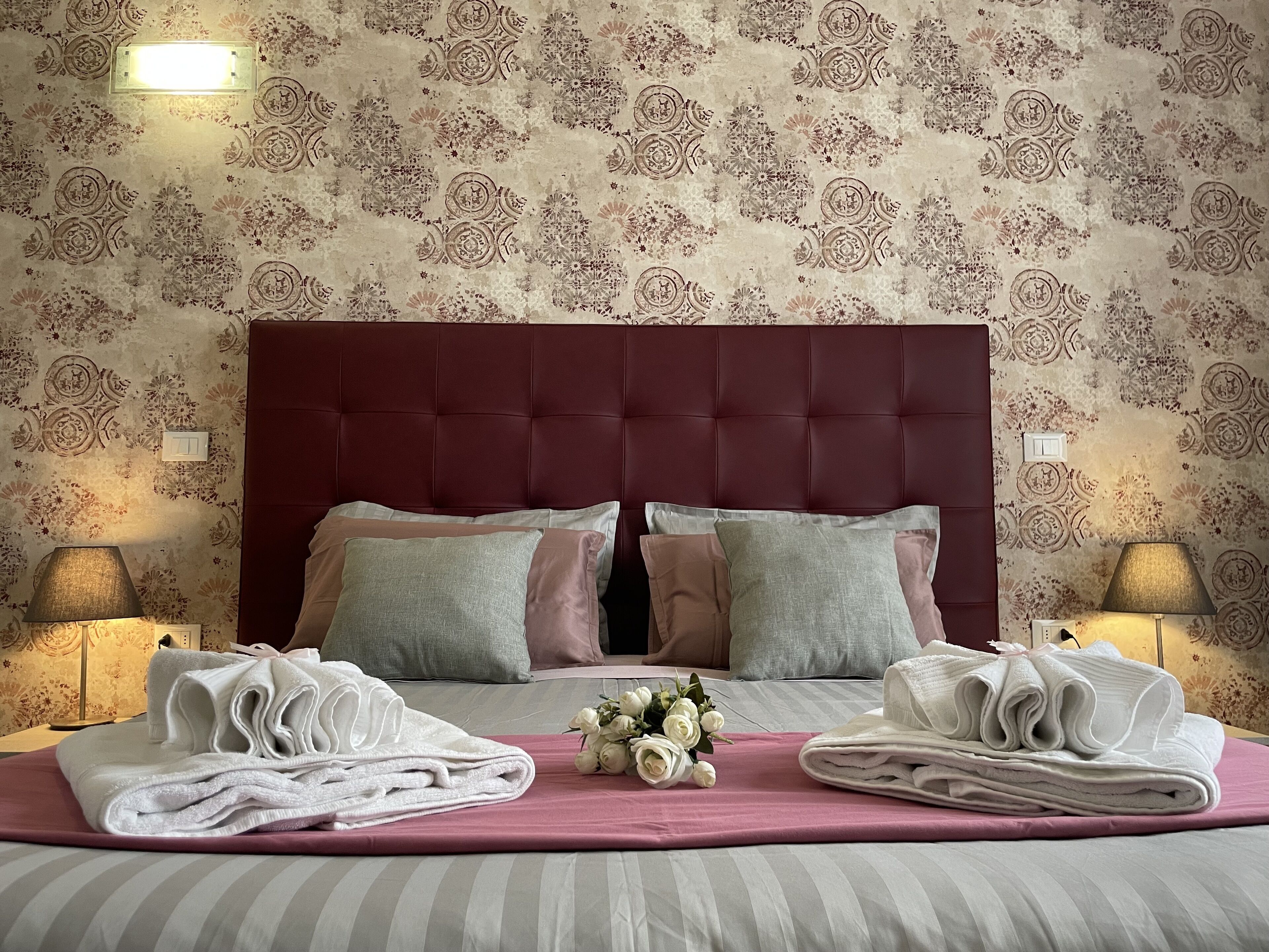 A neatly made bed with a striped bedspread, two pillows, and two folded towels.