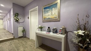 A hallway with a white door, a painting of a bridge, a radiator, and a table with decorative items. - Porta Alla Croce Guest House (Florence)
