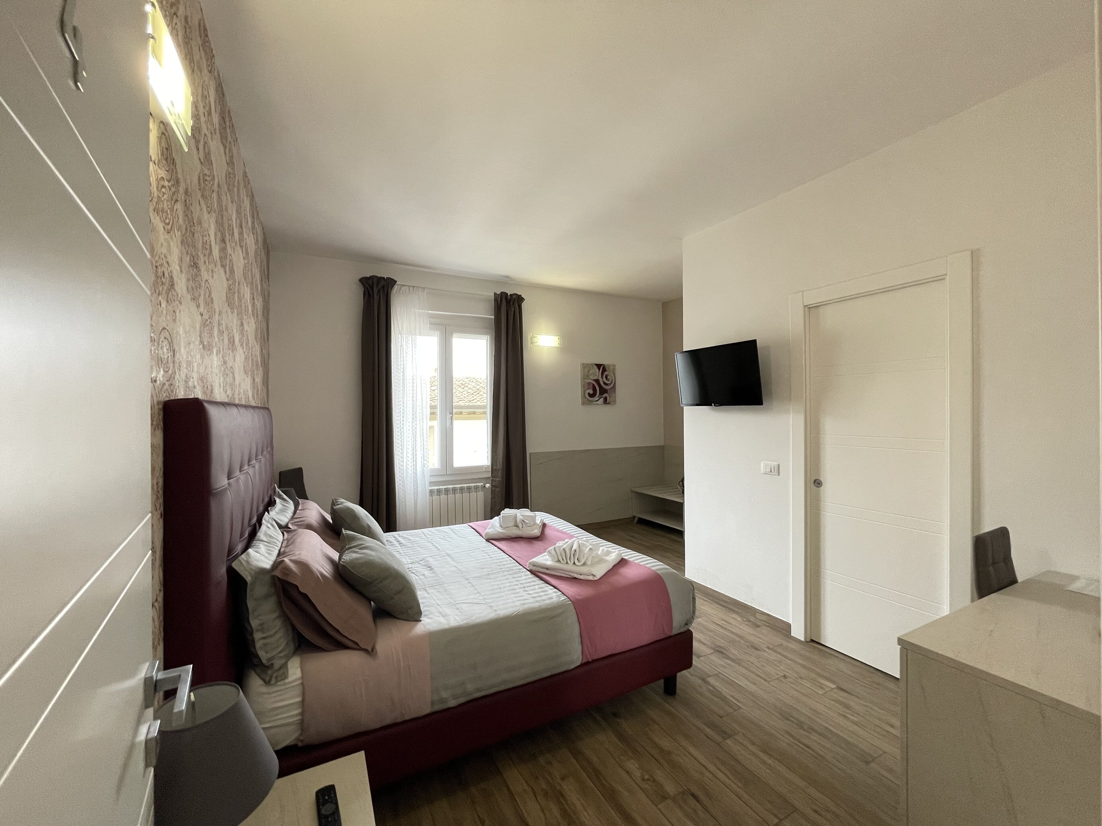 A bedroom with a bed, a TV mounted on the wall, and a door.