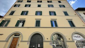 A multi-story building with a beige facade, green shutters, and a sign for UnipolSai Assicurazioni. - Porta Alla Croce Guest House (Florence)