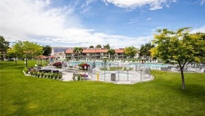 Et hotel med swimmingpool, omgivet af velplejede græsplæner og træer.