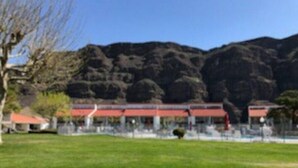 A building with a red roof and multiple windows, surrounded by a grassy area and trees. - #155- Kater's Kabin Condo near large pool & shuttle to Gorge Amp-book separately (Quincy)