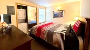 A hotel room with a bed, a desk, a television, and a door leading to a bathroom. - #155- Kater's Kabin Condo near large pool & shuttle to Gorge Amp-book separately (Quincy)