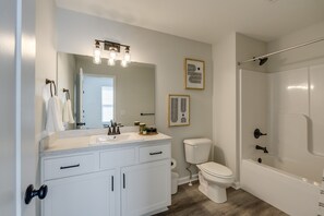 A modern bathroom with a sink, toilet, and bathtub.