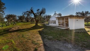 A small white building with a covered porch and a single dome roof, surrounded by trees and grass. - 3745 Trullo Puspo by Barbarhouse (Carovigno)