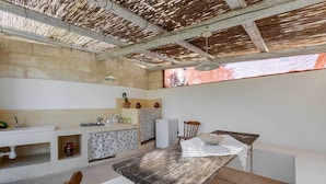 A rustic kitchen with a wooden table, a sink, and a refrigerator. - 3745 Trullo Puspo by Barbarhouse (Carovigno)