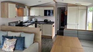 Een ruimtelijke woonruimte met een kitchenette, een bank en een eettafel.