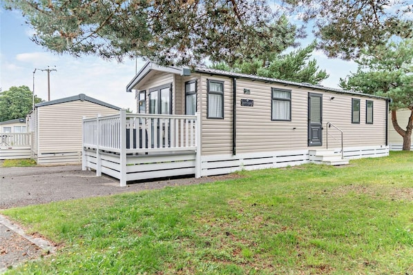 A mobile home with a porch, a small deck, and a front door.