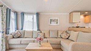 Een woonkamer met een beige bank, een houten salontafel en een ingelijst kunstwerk aan de muur.