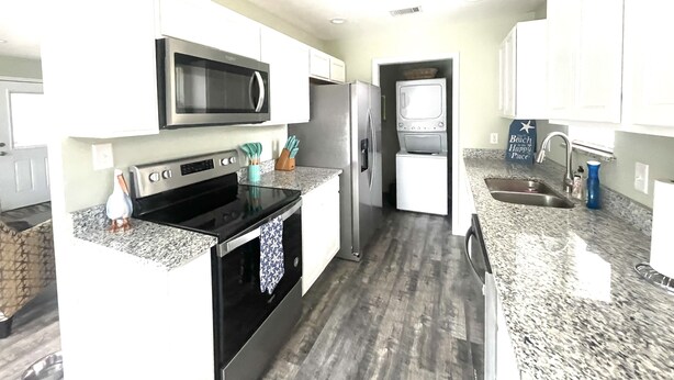 A modern kitchen with stainless steel appliances, granite countertops, and white cabinetry. - Cozy 2-bedroom 2 bath cottage in enjoyable Ocean Springs! Sleeps 4 guests. (Ocean Springs)