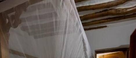 A room with a wooden bed, a green mattress, and a wooden door.