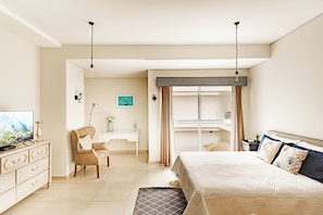 Ein Hotelzimmer mit einem Bett, einem Schreibtisch, einem Stuhl, einem Fernseher und einem Vorhangfenster.