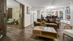 Een ruime woonkamer met een houten salontafel, een leren bank en een eethoek op de achtergrond.
