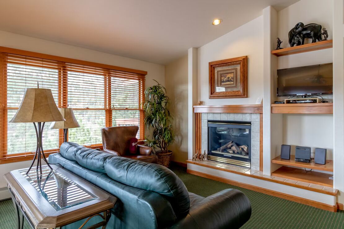 A living room with a fireplace, a sofa, a coffee table, and a television on a shelf.