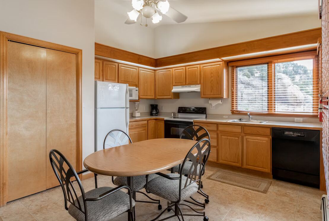 A compact kitchen with wooden cabinets, a refrigerator, a stove, and a dishwasher.