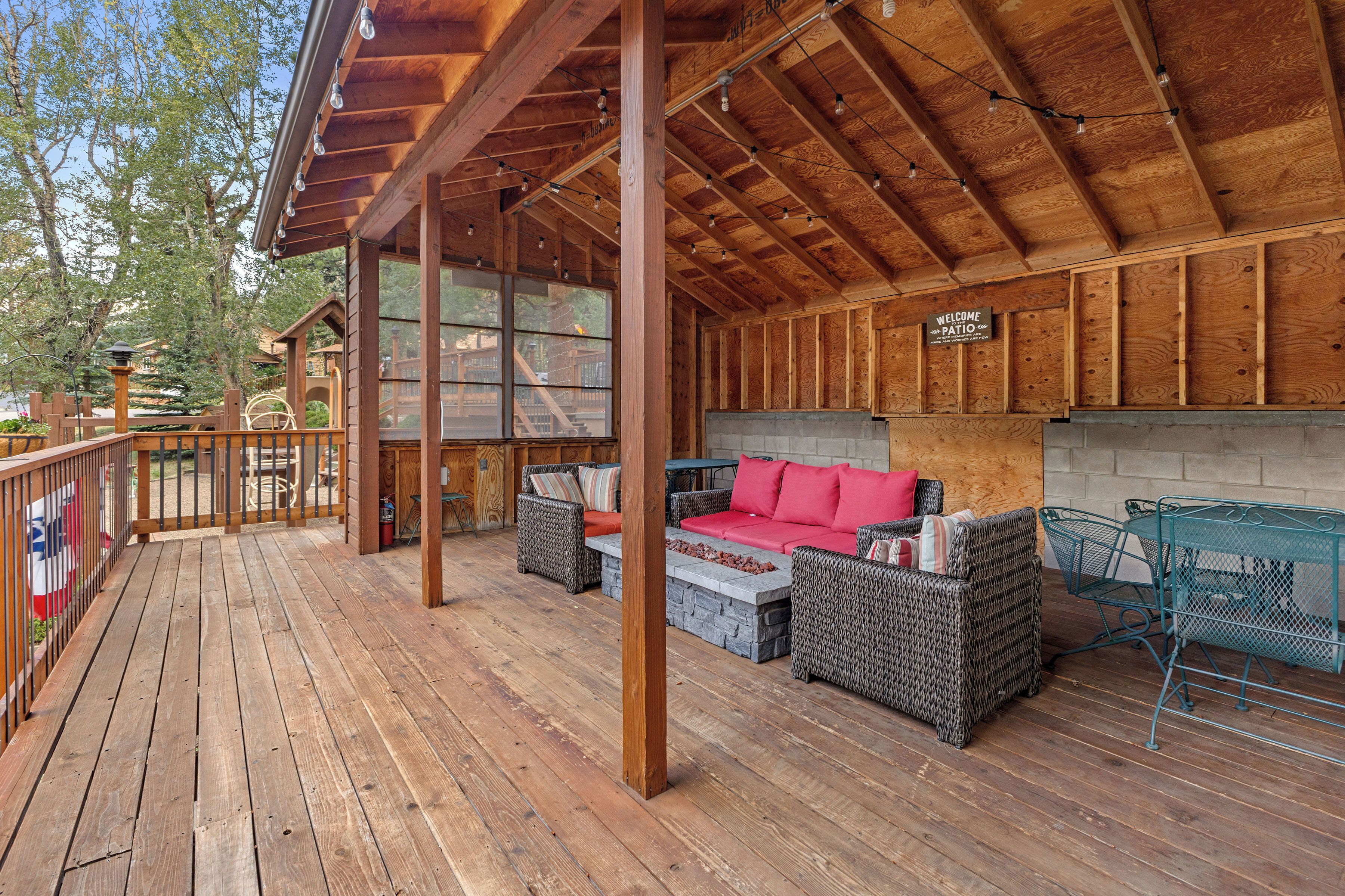 Une terrasse en bois avec des meubles en osier et un canapé rouge, une table en métal et une pancarte indiquant « Bienvenue sur la terrasse ».