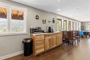 A kitchen with a wooden island, a coffee station, and a view of the outdoors.