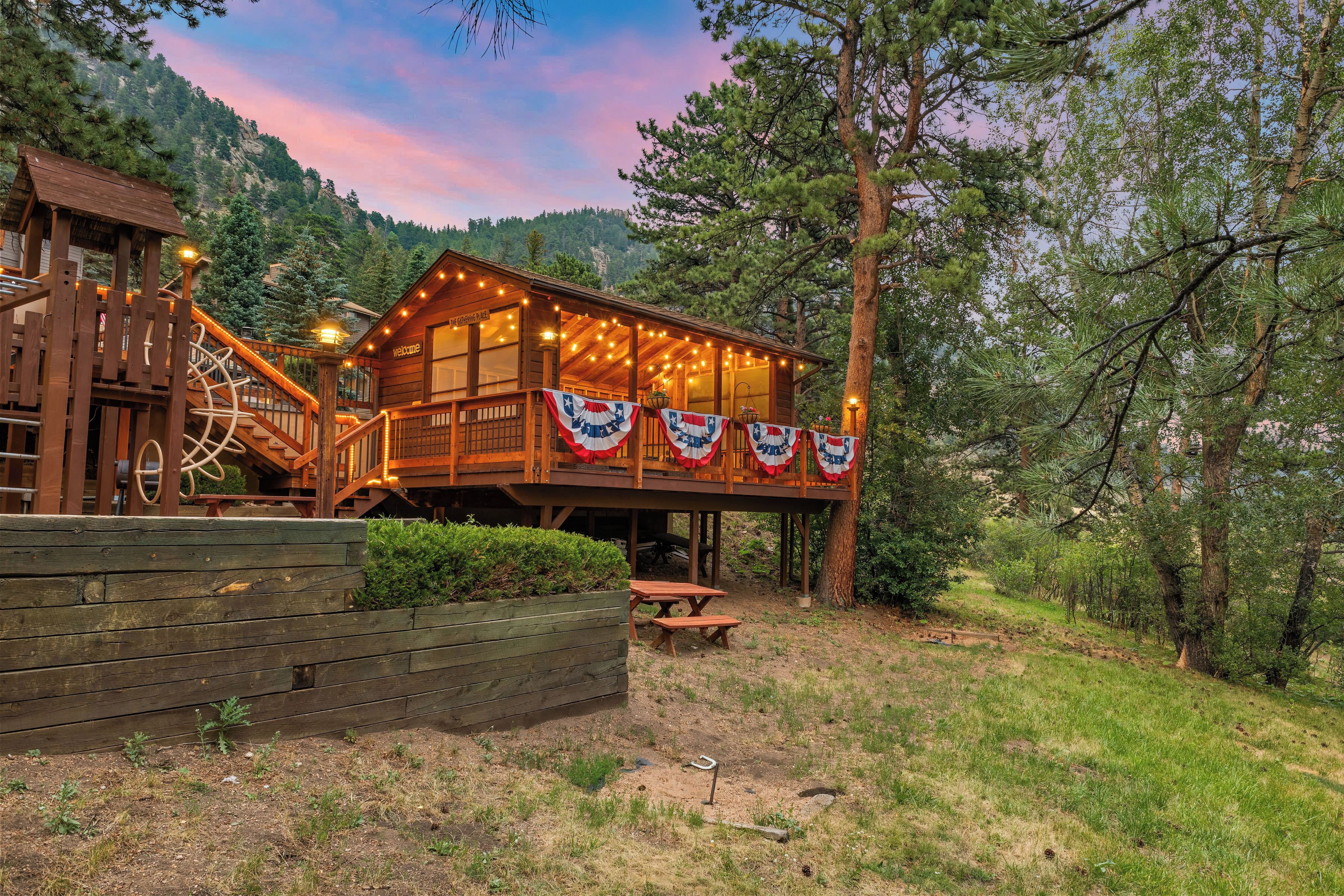 Une cabane en bois avec une terrasse, une roue à eau et une table de pique-nique.