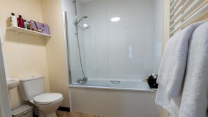 A bathroom with a toilet, sink, shower, and bathtub. - Wick Bay Apartments (Wick)