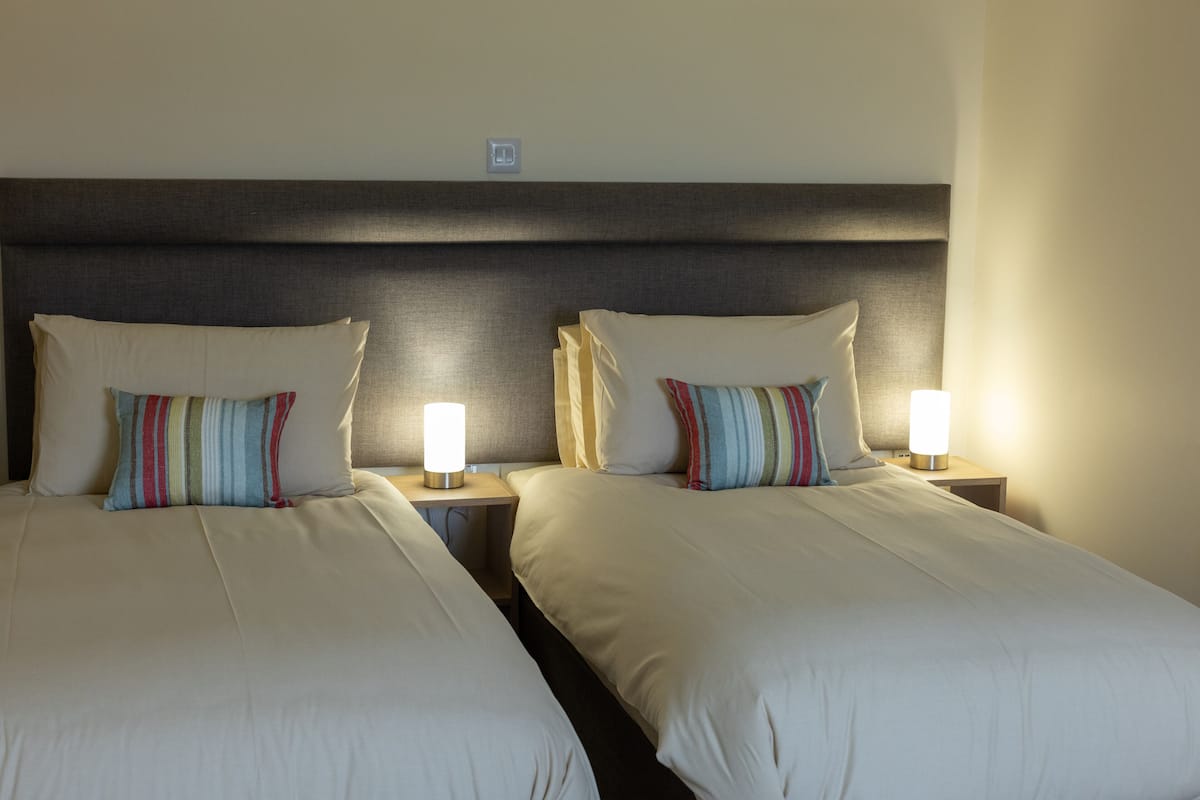 Two single beds with striped pillows and bedside lamps in a hotel room.
