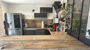 Una cucina moderna con piano in legno, mobili neri, frigorifero integrato e un'ampia finestra con piante.