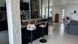 Una cucina moderna con isola centrale, sgabelli da bar, un ampio specchio e un'area pranzo con divano e sedie.