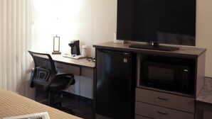 A hotel room with a bed, a desk, a television, a refrigerator, and a microwave. - The Lodge at Moorcroft (Moorcroft)