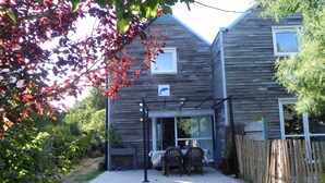 A wooden house with a covered patio and a fenced garden area. - Gîte Cozy à Deux pas de la mer (Le Conquet)