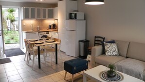 A compact living space with a kitchenette, dining area, and a sofa. - Gîte Cozy à Deux pas de la mer (Le Conquet)