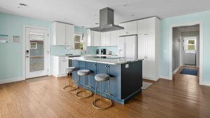 A modern kitchen with a central island, white cabinets, and a blue accent wall.
