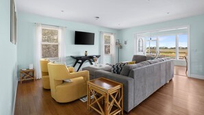 A living room with a sofa, chairs, a table, and a TV.
