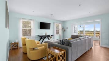 A living room with a sofa, chairs, a table, and a TV.