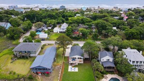 An aerial view of a coastal residential area with houses, a swimming pool, and a view of the ocean.