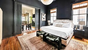 Un dormitorio moderno con una cama grande, suelo de madera y vistas a la ciudad a través de la ventana.