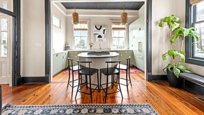 Una cocina moderna con una isla central, taburetes de bar e iluminación colgante.