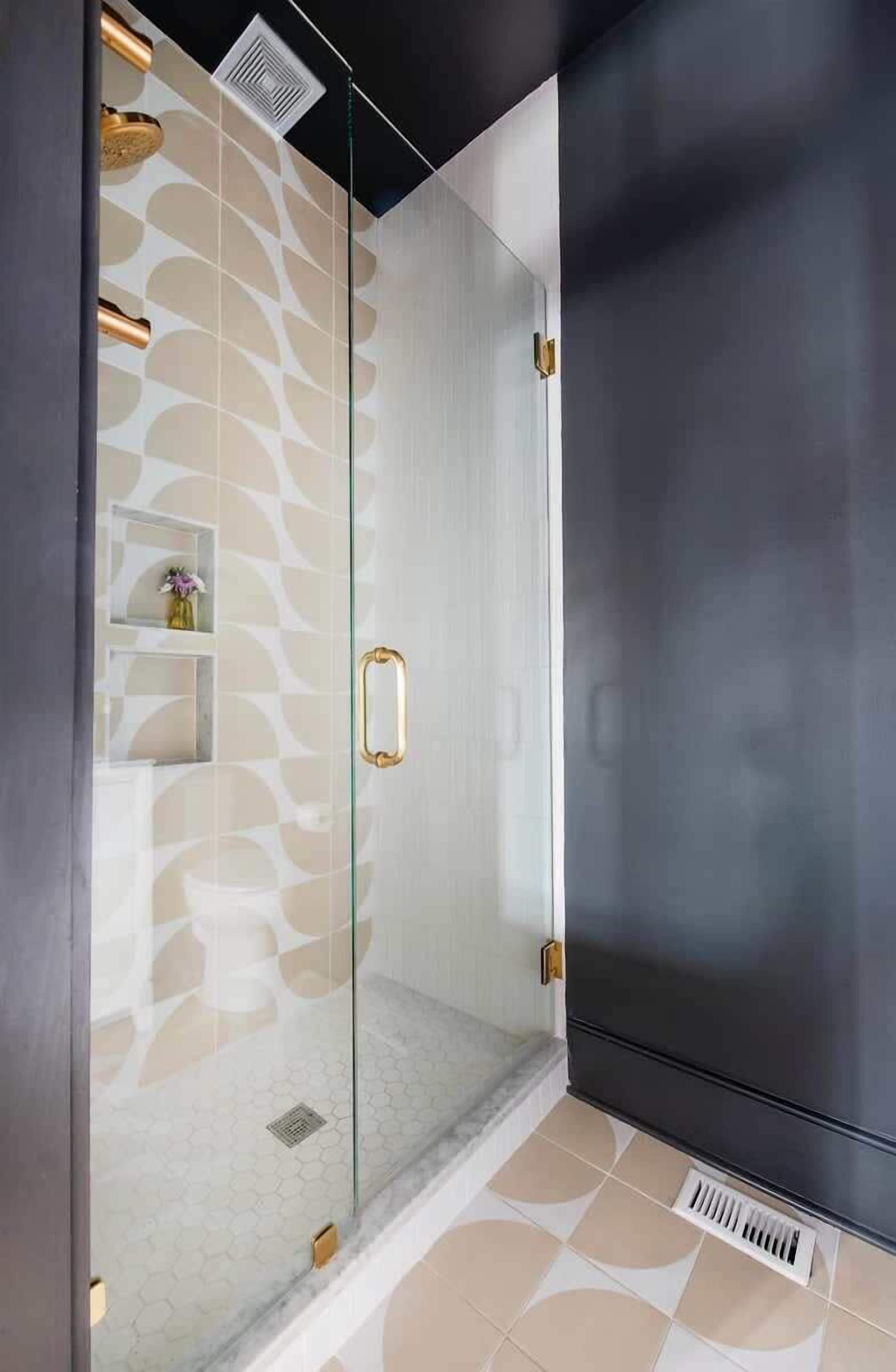 Ein modernes Duschgehäuse mit Glastür, Wand mit geometrischem Muster und schwarzem Wandpaneel.