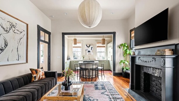 Una sala de estar moderna con un sofá negro, una mesa de centro de vidrio y una chimenea.