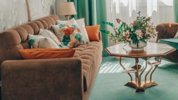 A living room with a brown sofa, a coffee table, and a wall with a leaf pattern. - pnoe d'Athènes (Athina)