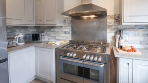Une cuisine moderne dotée d’appareils électroménagers en acier inoxydable, de meubles blancs et d’un mur de fond en briques.