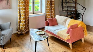 A cozy living room with a wooden ceiling, a sofa, a coffee table, and a spiral staircase.