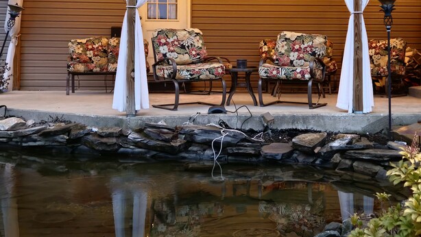 A covered outdoor seating area with floral-patterned chairs and a small pond. - Tranquility: near Carlisle, Harrisburg, Messiah, Lancaster, Hershey attractions (Dillsburg)