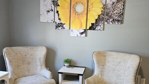 A room with two upholstered armchairs, a small side table with a plant, and a wall-mounted floral artwork. - Tranquility: near Carlisle, Harrisburg, Messiah, Lancaster, Hershey attractions (Dillsburg)