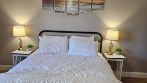 A neatly made bed with a white duvet, two bedside tables with lamps, and a wall with three sunset paintings. - Tranquility: near Carlisle, Harrisburg, Messiah, Lancaster, Hershey attractions (Dillsburg)