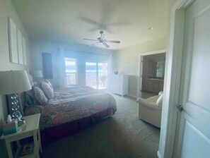 A bedroom with a bed, a ceiling fan, a nightstand, a chair, and a door leading to another room. - A66-Condo by pool & golf course (Quincy)