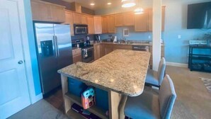 Eine moderne Küche mit Granit Arbeitsplatten, Edelstahlgeräten und Holzschränken.