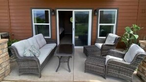 An outdoor patio with wicker furniture, a table, and a covered area. - A28 condo by large pool/shuttle (Quincy)